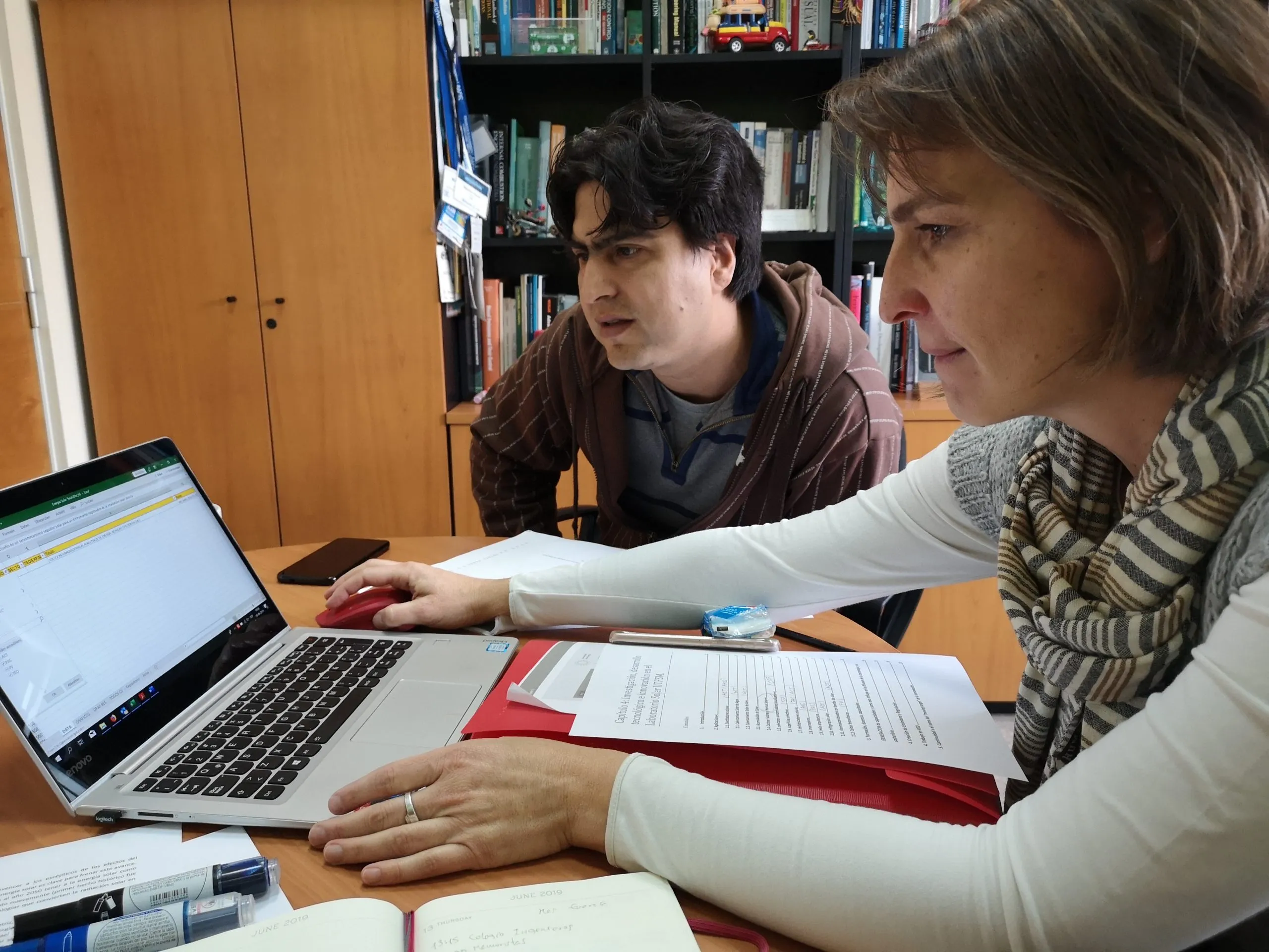 Dos investigadores revisando en un computador portátil el capítulo del libro sobre el Laboratorio Solar de la UTFSM.